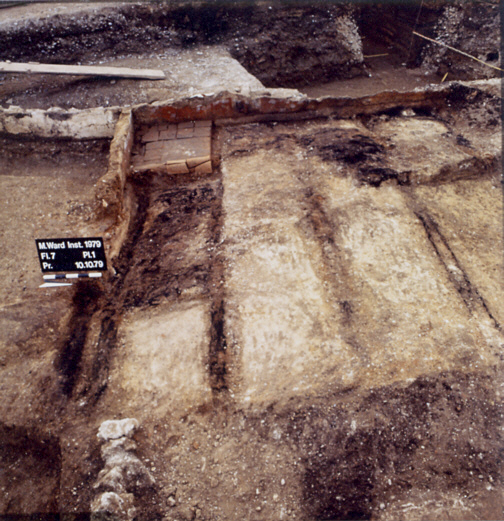 Maria-Ward-Institut (1979). Abdrücke hölzerner Unterzüge für einen Dielenboden in einem Haus aus dem 2. Jahrhundert. In hinteren Ecke Herd aus Ziegelplatten und Reste der rot bemalten Wand.